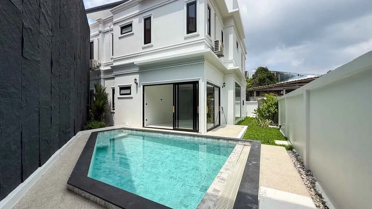 Chalong villa: white two-storey house with a slate-clad wall and an angular pool in the side garden.