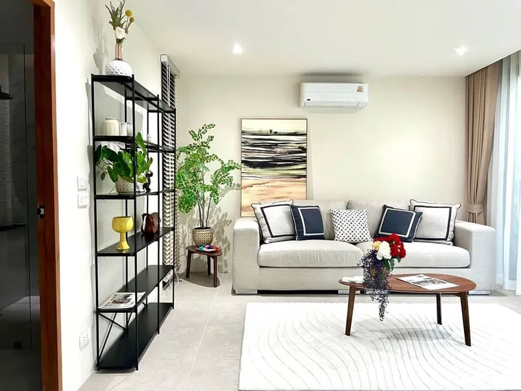 Living room with a white sofa, navy cushions and an open shelving unit with plants.