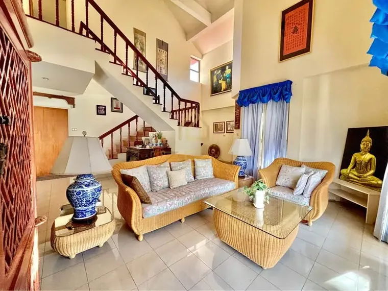 Living room with terracotta floor, a cream sofa set and glass doors open to the garden.