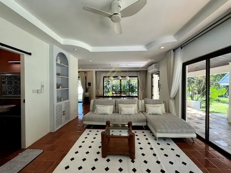 Living room with terracotta tiles, a black-and-white rug and a sliding door to the terrace.