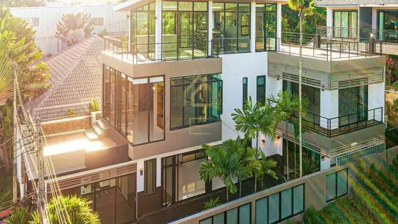 Rawai villa photographed from above: three storeys of glass and white render with terraces stepping down to the garden.