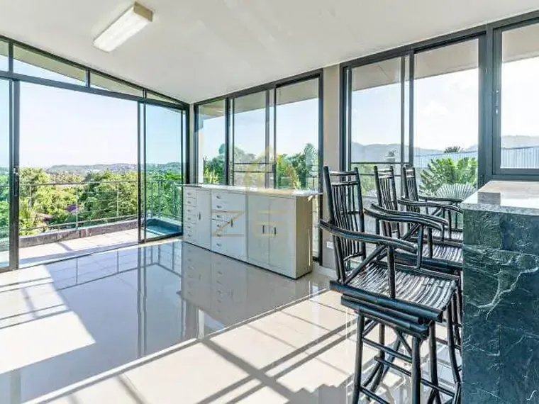 Glass-walled upper room with a bar and stools, the hills and the view beyond the windows.