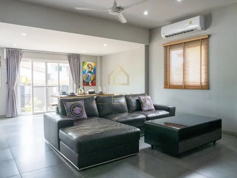 Living room with a black leather corner sofa, a ceiling fan and a timber-framed window.