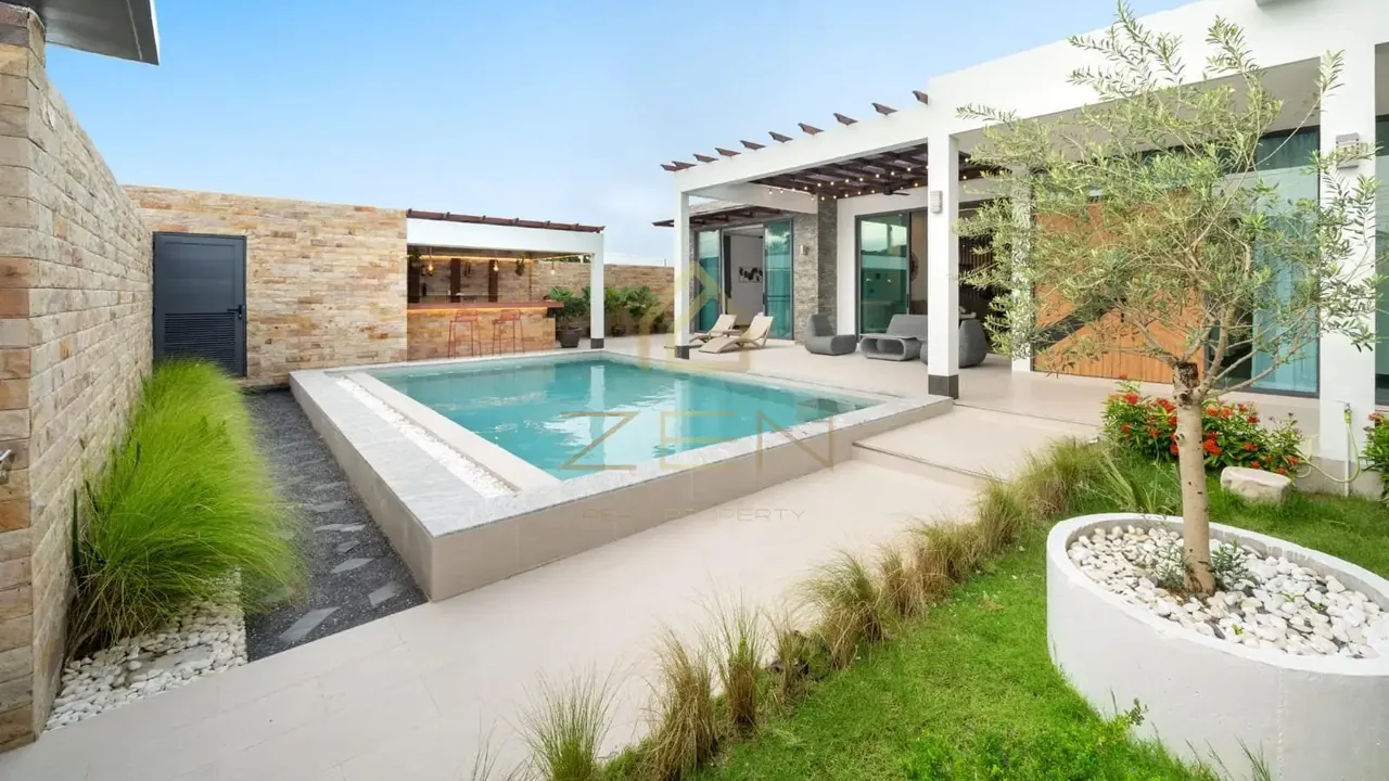 Ban Don villa: raised pool with a stone wall, pergola bar and a single-storey pavilion behind.