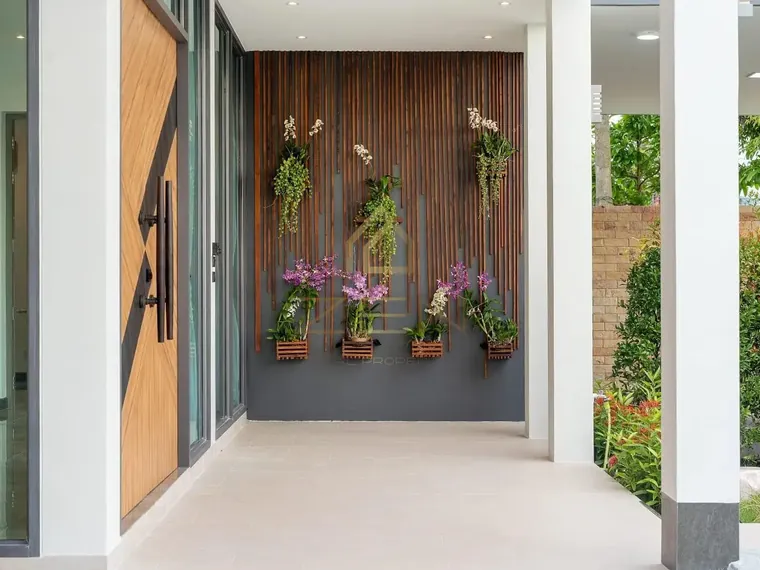 Timber entrance door with orchids mounted on the wall beside it.