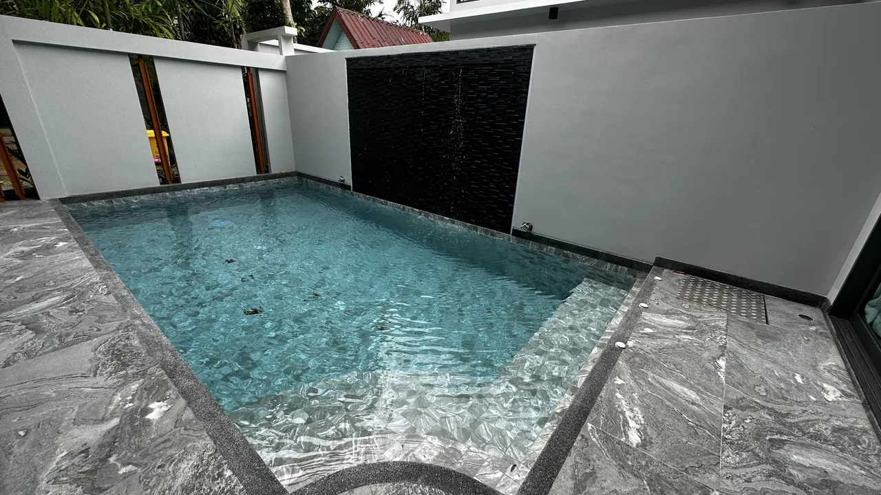 Rawai two-bedroom villa: private pool with a black stone water wall and grey stone terrace.