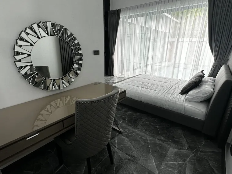 Furnished bedroom with a dressing table, round mirror and dark marble floor.