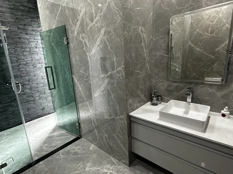 Marble bathroom with a walk-in glass shower and a wall-hung basin.