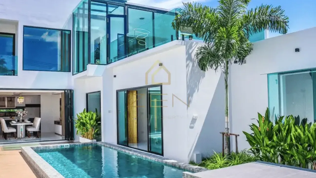 Rawai three-bedroom villa: pool in front of a two-storey white house with a glass upper room and a tall palm.