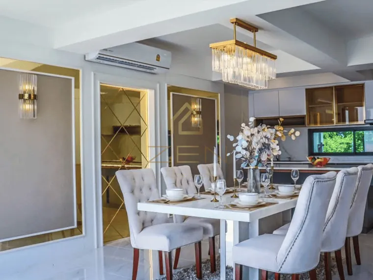 Dining room with a white table for eight, chandelier and gold detailing.